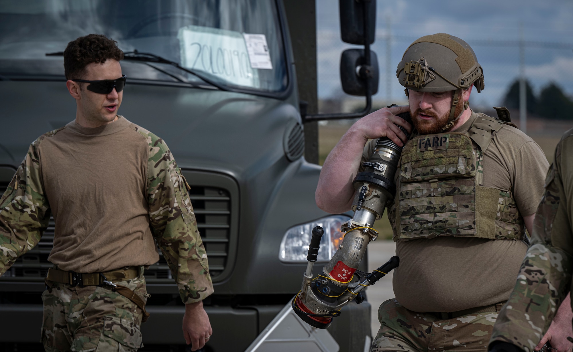 U.S. Air Force Senior Airman Clint Helgoth, right, 100th Logistics Readiness fuels facilities technician, pulls a fuel hose over his shoulder during his forward area refueling point team tryout at RAF Mildenhall, England, March 14, 2025.