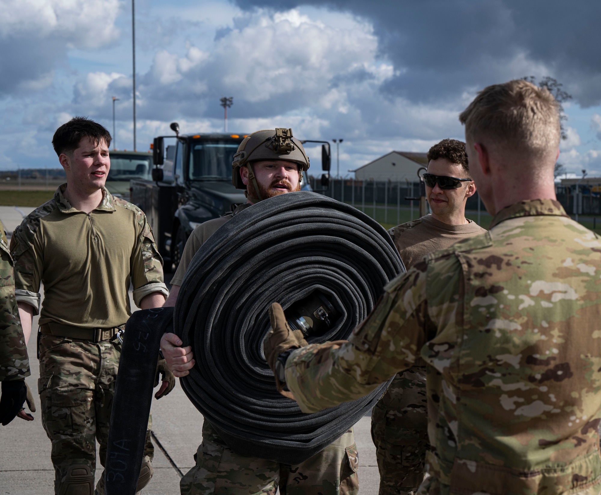 U.S. Air Force Senior Airman Clint Helgoth, center, 100th Logistics Readiness Squadron fuels facilities technician, passes a fuel hose during his forward area refueling point team tryout at RAF Mildenhall, England, March 14, 2025.