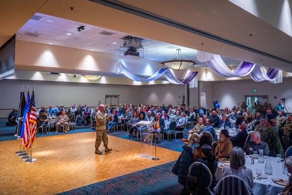 A man in uniform talks to a crowd of people.