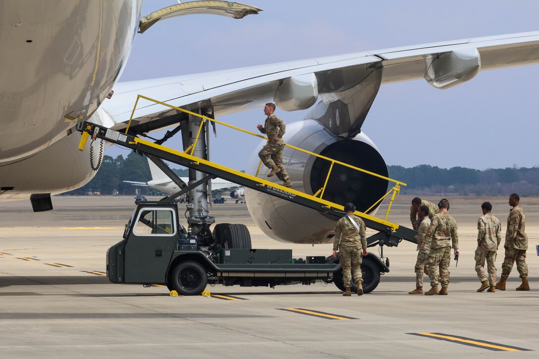 A soldier walks up a ramp attached to the opening of an aircraft.