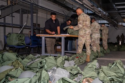 Members of the 11th Wing are issued individual protective equipment by 11th Logistic Readiness Squadron staff for a pre-deployment function line during an exercise on Joint Base Anacostia-Bolling, Washington, D.C., March 12, 2025. The 11th WG regularly conducts exercises to ensure constant readiness, streamline lethality and maintain strategic advantage. (U.S. Air Force photo by Hayden Hallman)