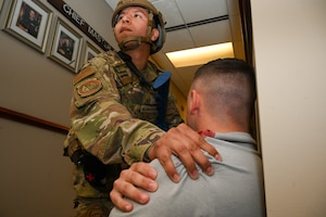 U.S. Air Force Airman 1st ClassBrian Maldonado Villegas, a ground transportation journeyman with the 11th Security Forces Squadron on Joint Base Anacostia-Bolling, compresses the simulated shoulder wound of U.S. Space Force Spc. 4 Cameron Matthews, a ceremonial guardsman with the U.S. Space Force Honor Guard on JBAB, during a combat readiness exercise at JBAB, March 11, 2025. The exercise tested the base’s mission readiness and capabilities during an active shooter scenario. (U.S. Air Force photo by Airman 1st Class Shanel Toussaint)