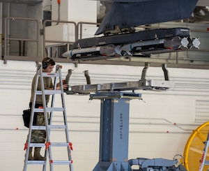 An Airman loads munitions on an aircraft.