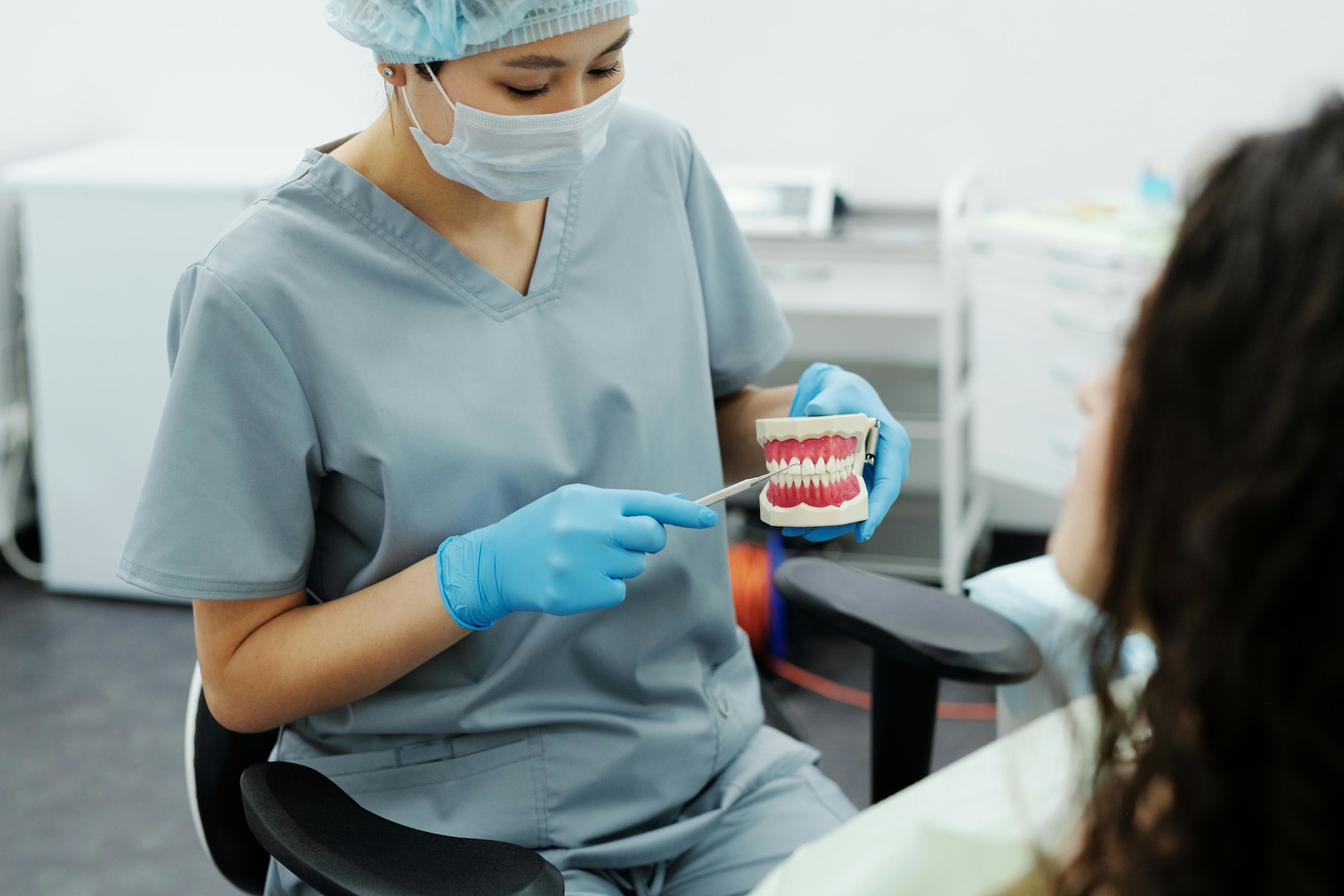 Woman in medical scrubs holds up model teeth.