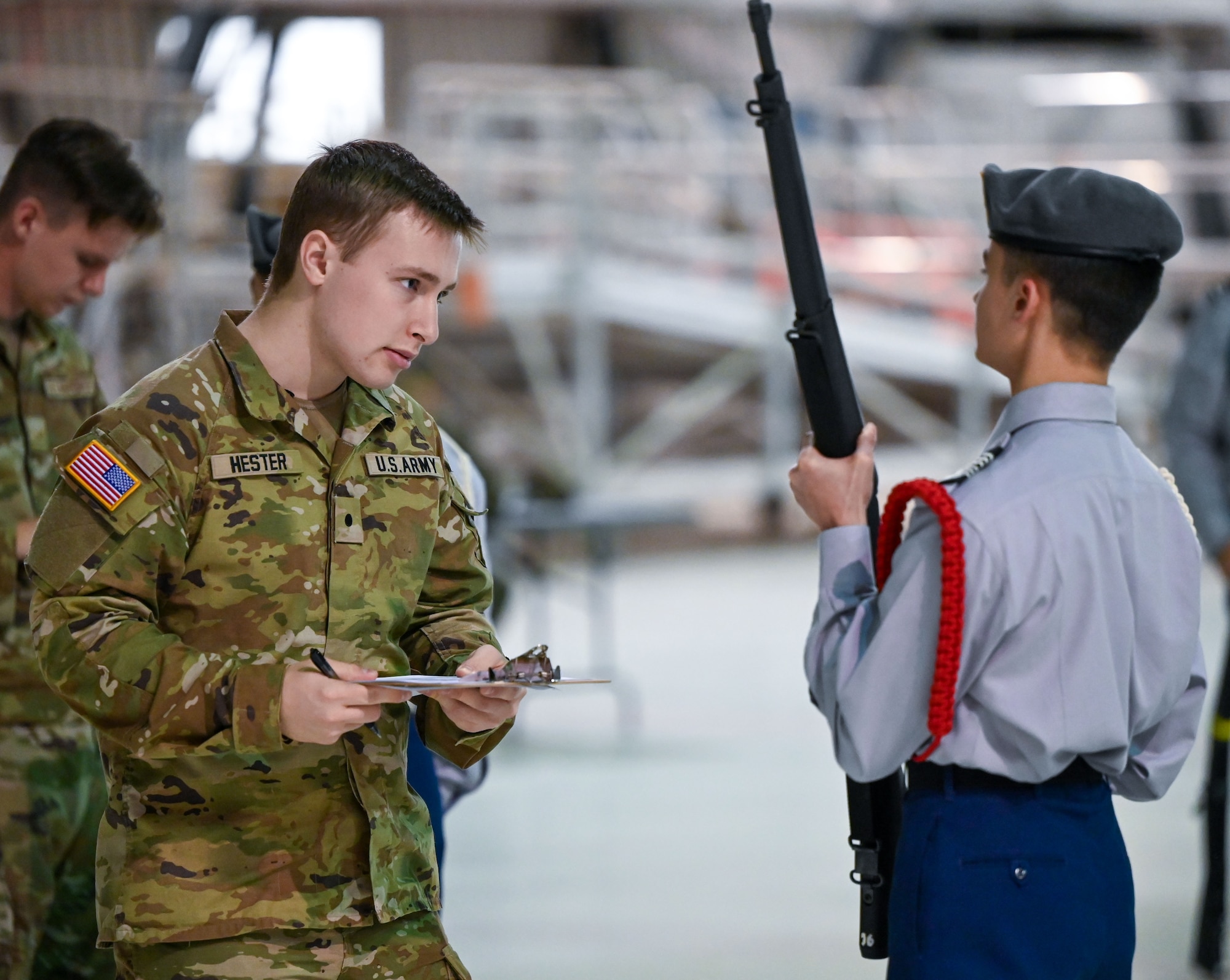 A judge evaluates a Junior Reserve Officers' Training Corps (JROTC) cadet during an armed drill inspection at the JROTC Drill Competition at Tinker Air Force Base, Oklahoma, Feb. 15, 2024. The event, returning to base after more than 20 years, featured regulation drills, color guard performances, and exhibition routines. (U.S. Air Force photo by Garrett N. Cole)