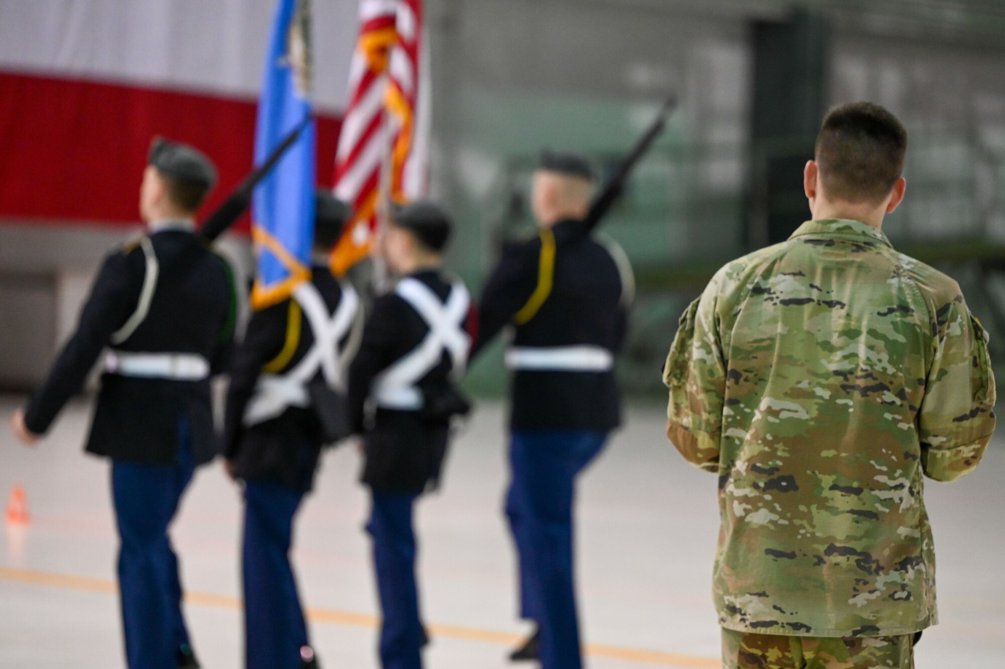 A judge observes a Junior Reserve Officers' Training Corps (JROTC) color guard team as they perform during the JROTC Drill Competition at Tinker Air Force Base, Oklahoma, Feb. 15, 2024. The competition, returning to base for the first time in more than 20 years, featured precision marching, color guard presentations, and exhibition drills. (U.S. Air Force photo by Garrett N. Cole)