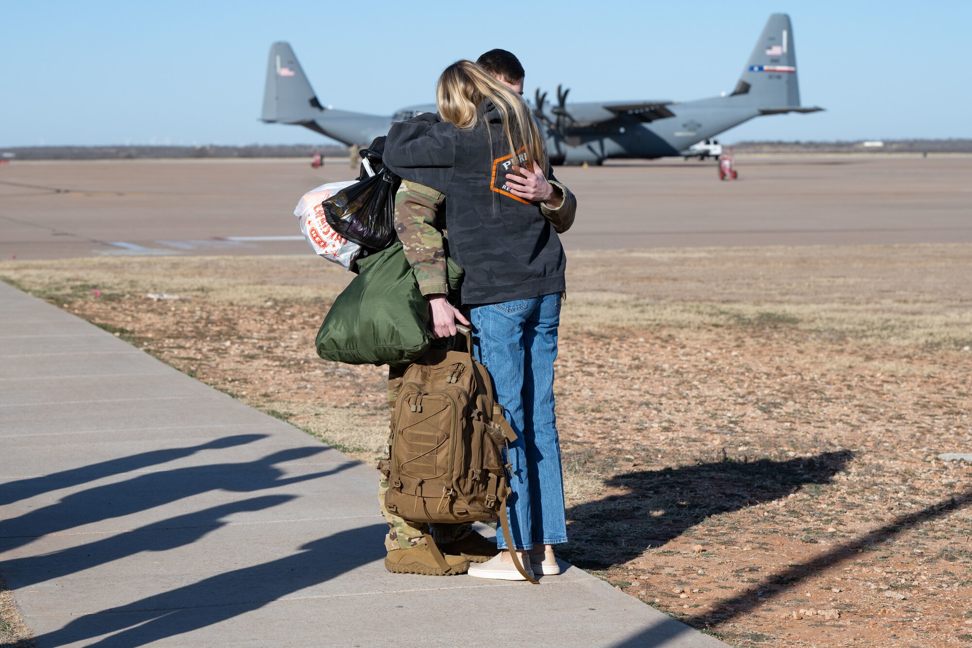 An Airman assigned to the 317th Airlift Wing embraces and says goodbye to a loved one at Dyess Air Force Base, Texas, Feb. 25, 2025, before departing for a deployment to the U.S. Central Command area of responsibility. The 317th AW provides tactical airlift capabilities including airdrop and aeromedical evacuation, utilizing the C-130J’s versatility and advanced capabilities. (U.S. Air Force photo by Senior Airman Emma Anderson)