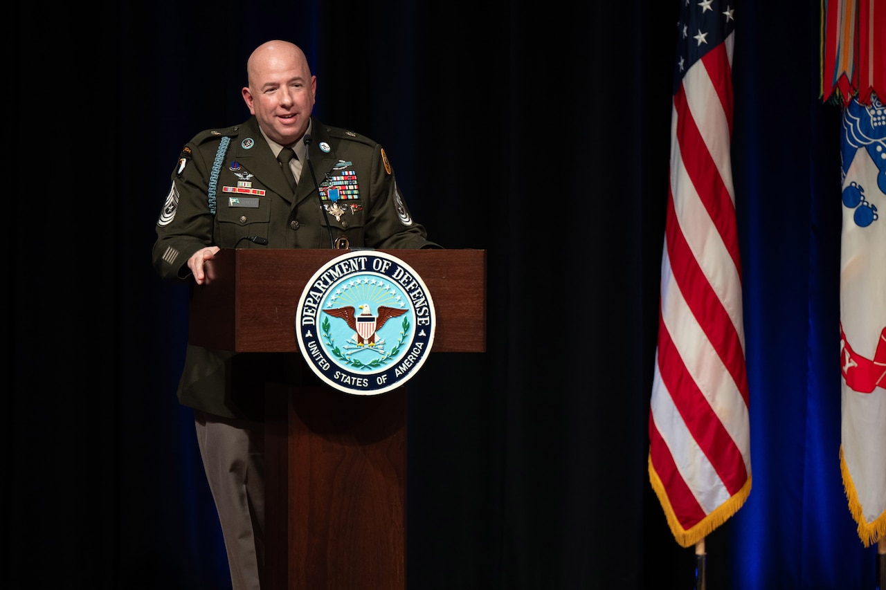 A soldier speaks at a podium behind a lectern.