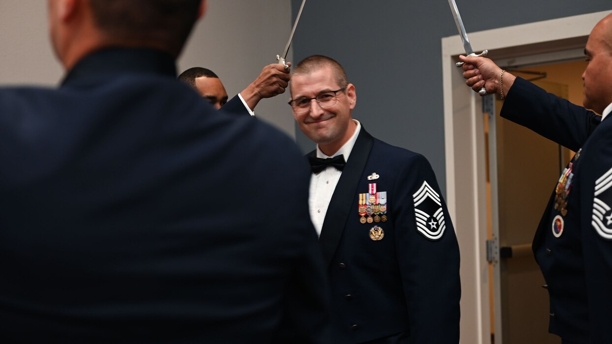 U.S. Air Force Chief Master Sgt. Brandon Abbott, 17th Training Group senior enlisted leader, walks through the saber arch as part of the 2025 Chief Recognition Ceremony in the Powell Event Center at Goodfellow Air Force Base, Texas, March 14, 2025. Six service members lined up in pairs and made an arch with their sabers for the honorees to walk under before the ceremony. (U.S. Air Force photo by Senior Airman Evelyn J. D’Errico)