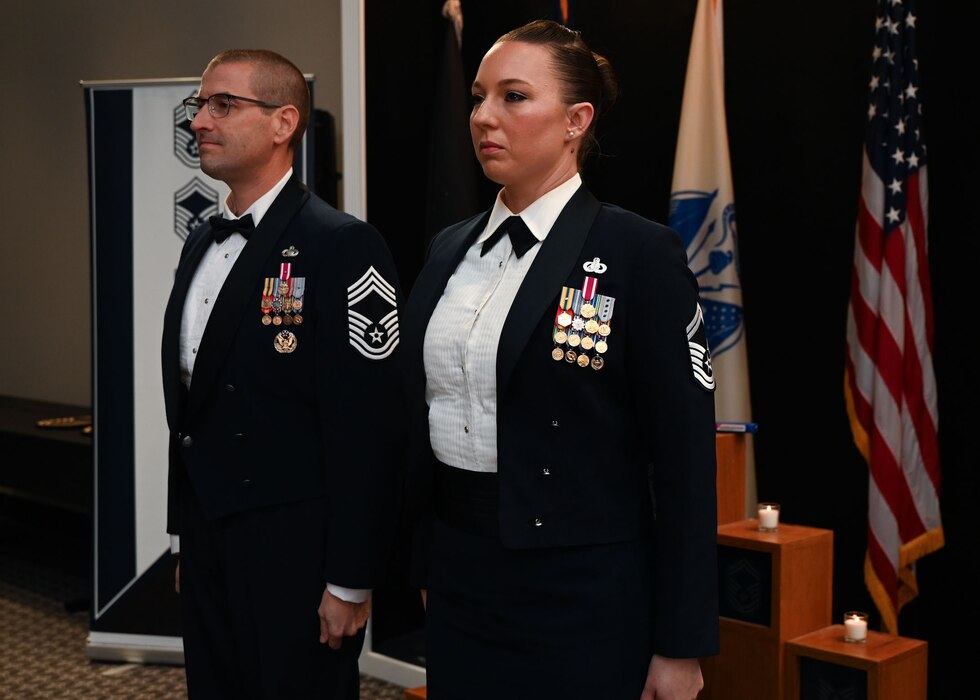 U.S. Air Force Chief Master Sgt. Brandon Abbott, 17th Training Group senior enlisted leader, left, and Chief Master Sgt. select Jessica Thompson, 17th Force Support Squadron senior enlisted leader, stand at the position of attention during the reading of the Chief’s Creed at the 2025 Chief Recognition Ceremony in the  Powell Event Center at Goodfellow Air Force Base, Texas, March 14, 2025. The rank of chief master sergeant makes up only one percent of the Air Force’s enlisted personnel. (U.S. Air Force photo by Senior Airman Evelyn J. D’Errico)