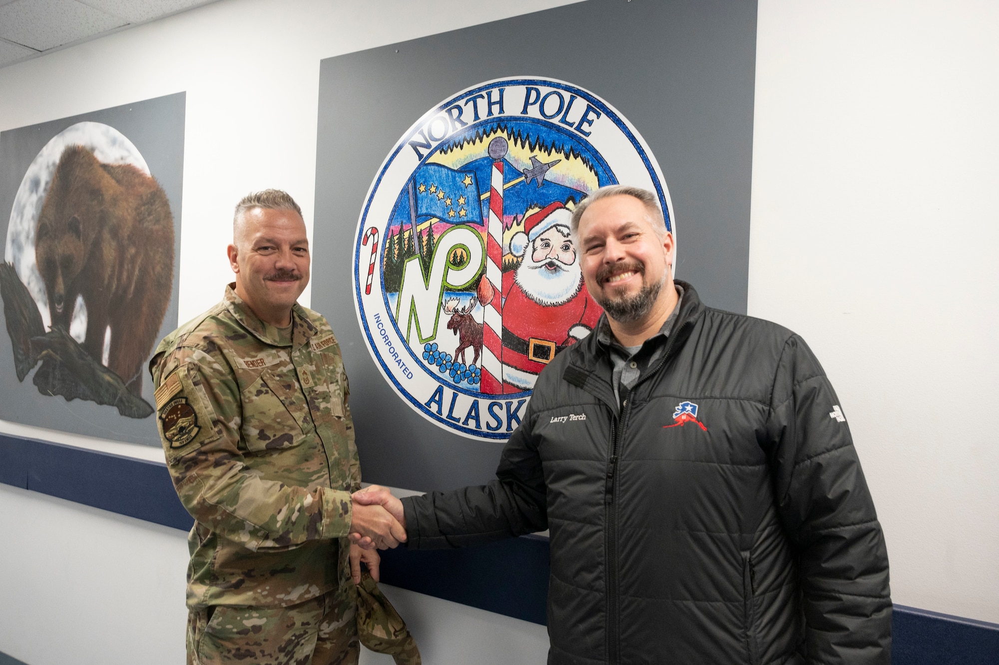 North Pole Mayor Larry Terch poses for a photo with Chief Master Sgt. George Bender in front of an Alaska Air National Guard KC-135 nose art panel displayed in the halls at the 168th Maintenance Group.