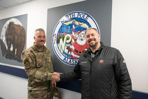 North Pole Mayor Larry Terch poses for a photo with Chief Master Sgt. George Bender in front of an Alaska Air National Guard KC-135 nose art panel displayed in the halls at the 168th Maintenance Group.