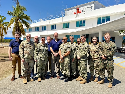 GUANTANAMO BAY, Cuba (Feb. 27, 2025) – Front row, from left, Brig. Gen. John Andrus, Joint Staff Surgeon; U.S. Navy Capt. Tammy Servies, director of U.S. Naval Hospital Guantanamo Bay, commanding officer of U.S. Navy Medicine Readiness and Training Command Guantanamo Bay, commander of Joint Medical Group, Joint Task Force Guantanamo Bay; and Dr. Steven Ferrara, Acting Assistant Secretary of Defense for Health Affairs, pose for a photo with members of his delegation and personnel from U.S. Naval Hospital Guantanamo Bay outside the hospital. The visit provided an opportunity to discuss medical readiness and health care initiatives at the installation. (U.S. Navy photo by Emily McCamy)