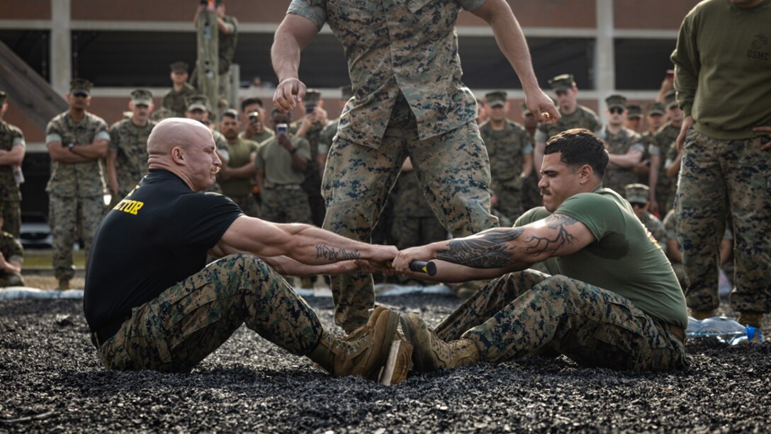 U.S. Marine Corps Staff Sgt. Geoffry Laney, left, an instructor at the Marine Corps Engineer School, Training Command, and Cpl. Jagger Robinson, a quality control non-commissioned officer with 8th Engineer Support Battalion, 2d Marine Logistics Group, mas-wrestle on Marine Corps Base Camp Lejeune, North Carolina, March 13, 2025. In honor of the patron saint of engineers, St. Patrick, the Marine Corps Engineer School hosted a field meet for engineers across Marine Corps Installations East and came together to compete in 14 engineer-themed events. (U.S. Marine Corps photo by Lance Cpl. Judith Ann Lazaro)