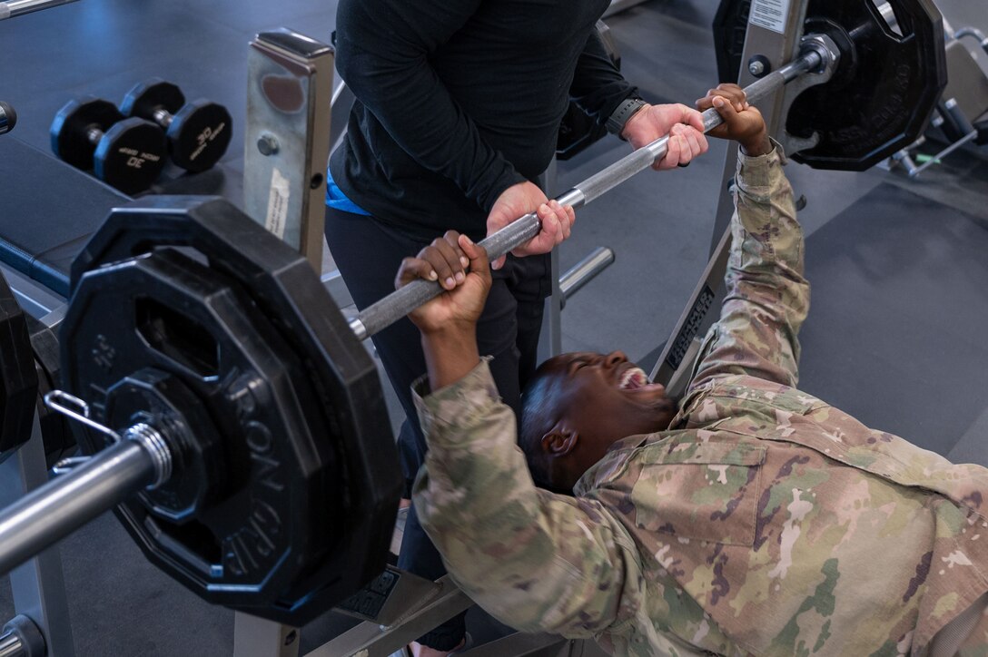Airman lifts barbell with help from another man. (U.S. Air Force Photo by Airman 1st Class Donnell Ramsey)