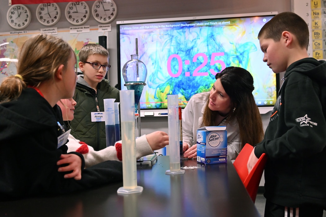 Students and teacher look at graduated cylinder