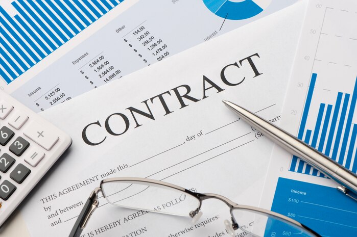 A contract with glasses a pen and a calculator.
