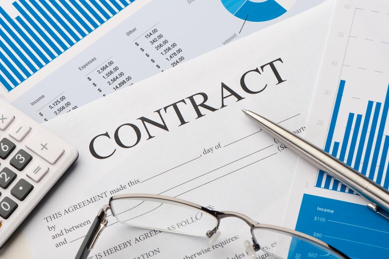 A contract with glasses a pen and a calculator.