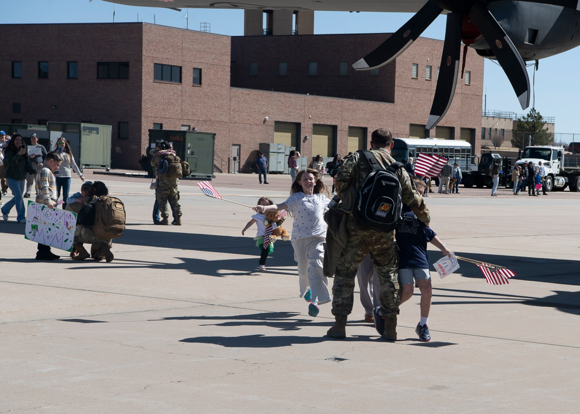 A family running towards each other in front of a military aircraft.