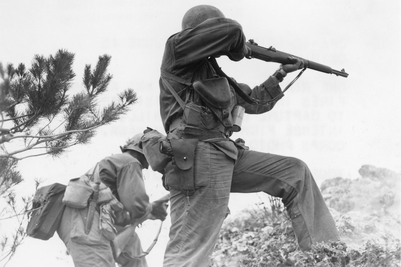 Two men holding weapons stand on a hill ready to attack an enemy.