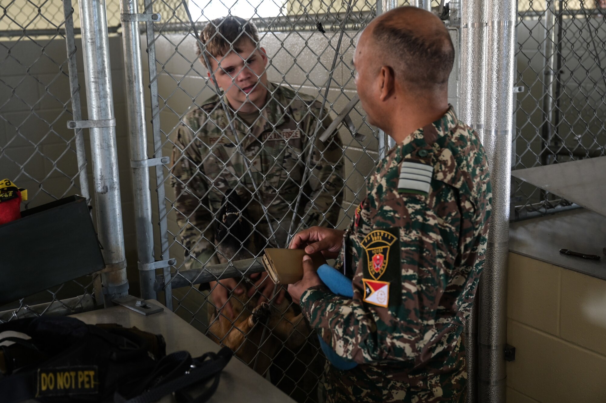 An U.S. Airman inside of a K-9 kennel speaks to a foreign visitor.