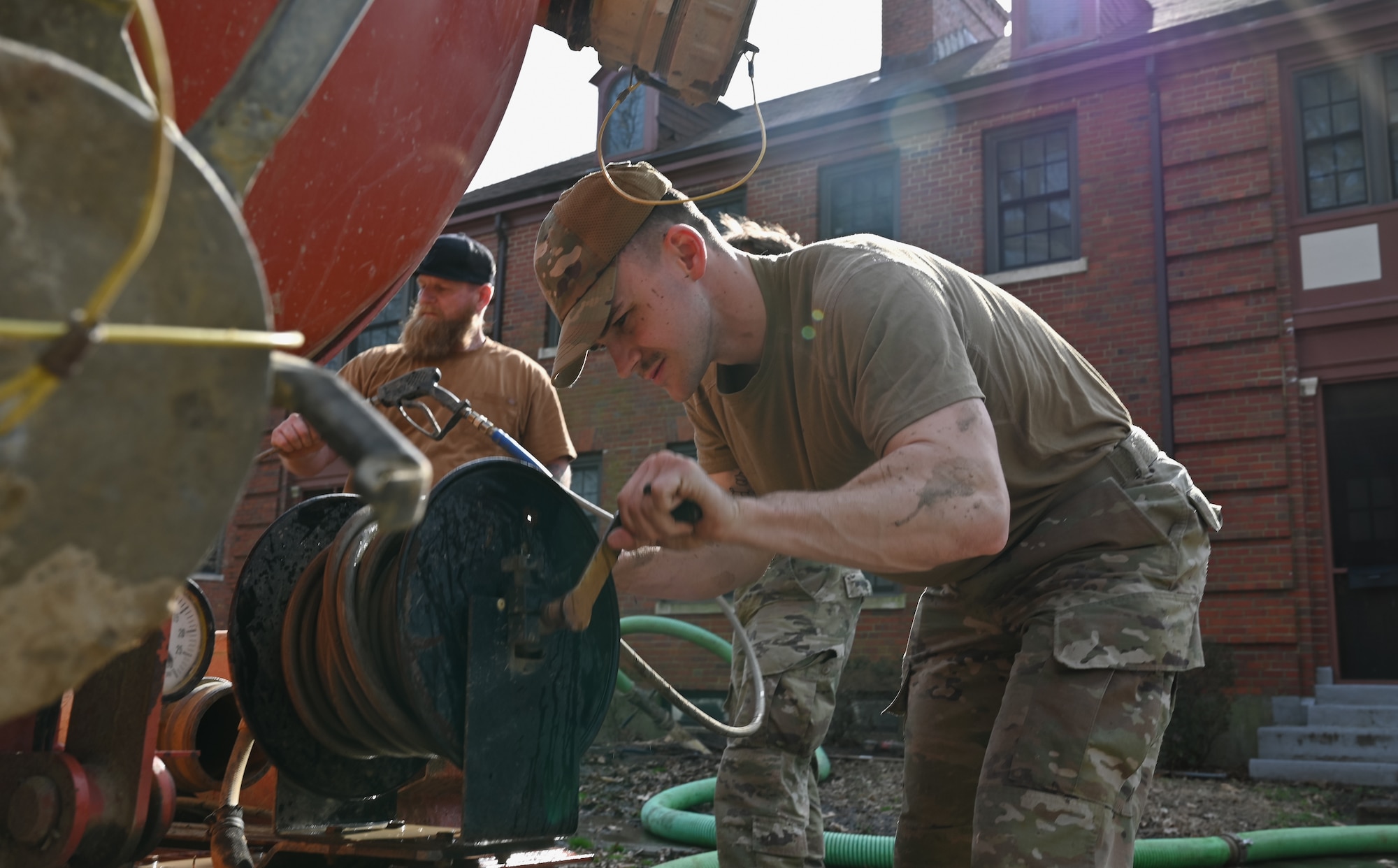 Airmen winds up a hose.