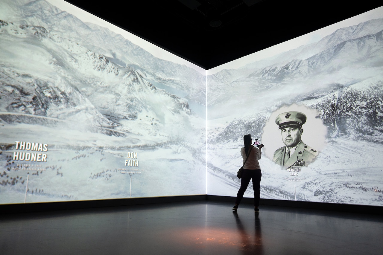 A 50-foot interactive screen in the corner of a room plays a video as a person stands in front of it.
