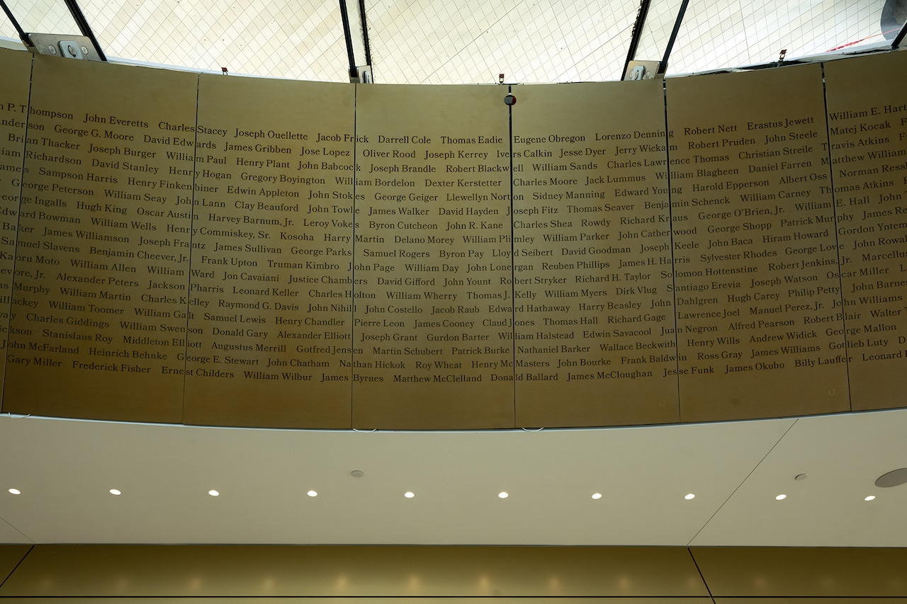 Hundreds of names are etched into panels on the ceiling plates of a building.