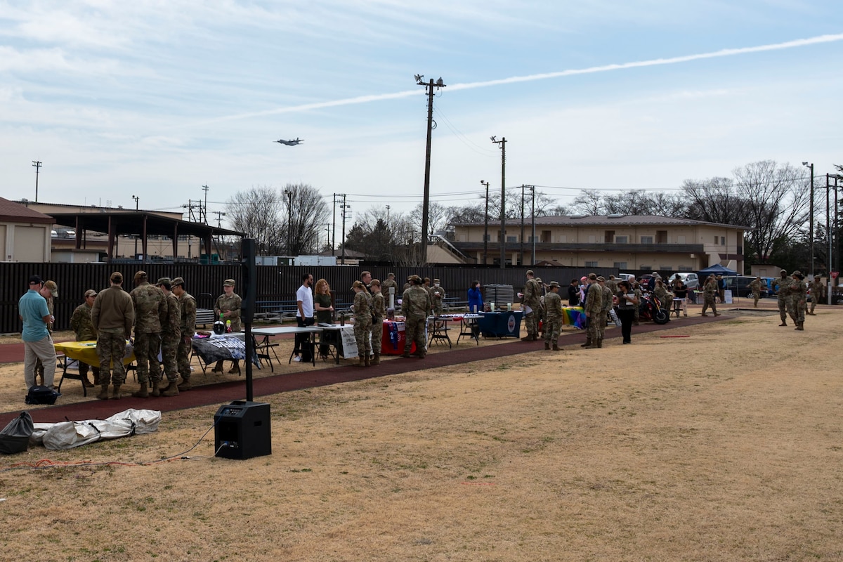 Community members participate in a club fair on a grass field.