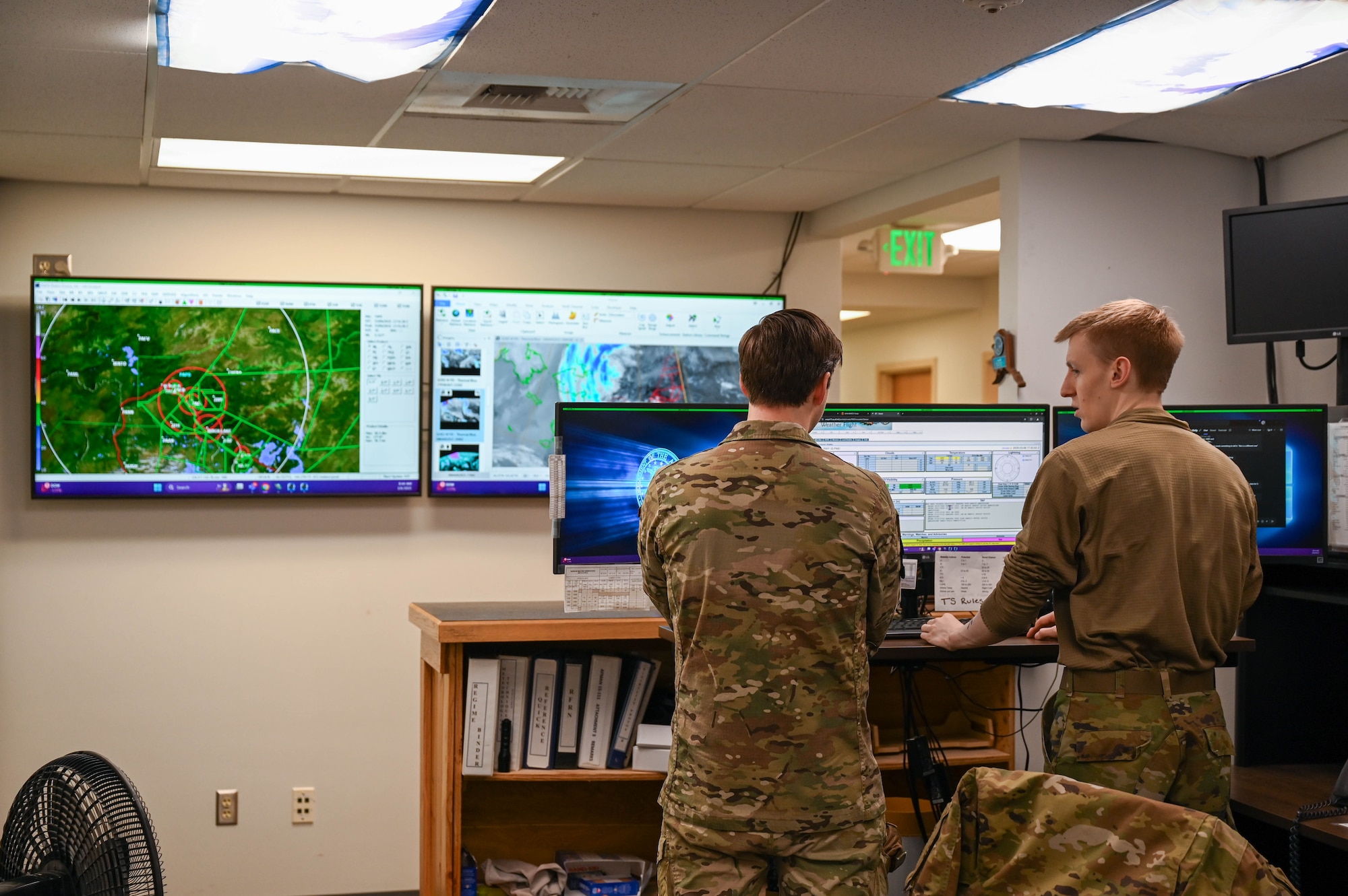U.S. Air Force Master Sgt. Gabriel Teager, left, 354th Operations Support Squadron weather flight chief, and Senior Airman Jered Pradel, 354th OSS weather forecaster, discuss temperature and weather patterns at Eielson Air Force Base, Alaska, March 6, 2025.
