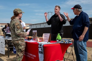 A military member speaks to two civilians during a job fair.