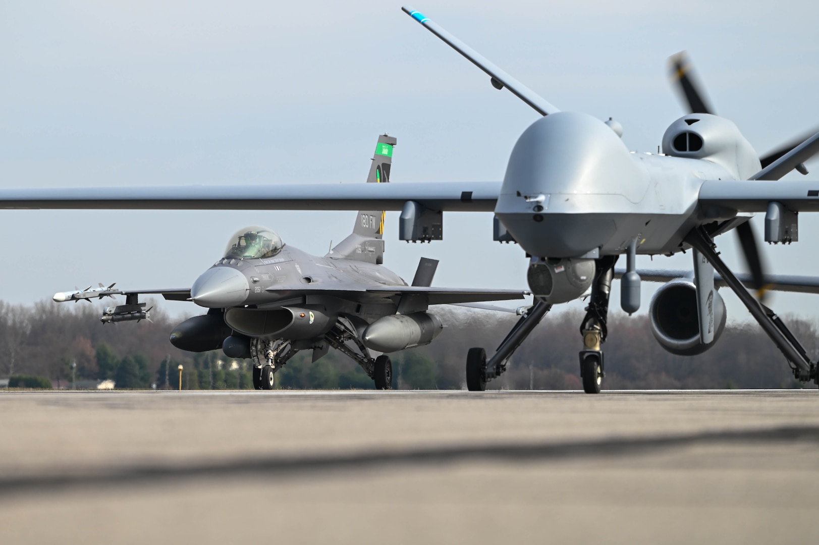 An MQ-9 Reaper assigned to the 178th Wing and an a F-16C Fighting Falcon from the 180th Fighter Wing participate in a close formation taxi "elephant walk" on Springfield-Beckley Air National Guard Base March 19, 2025.