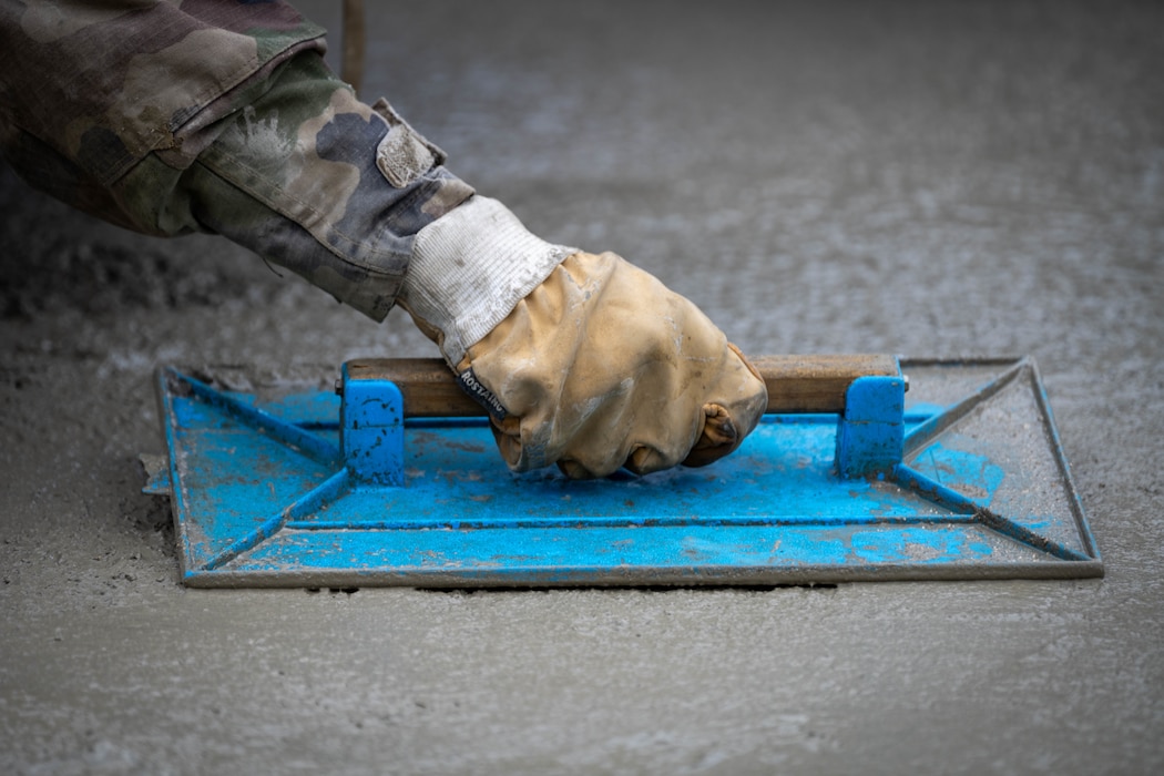 French army member smooths concrete.