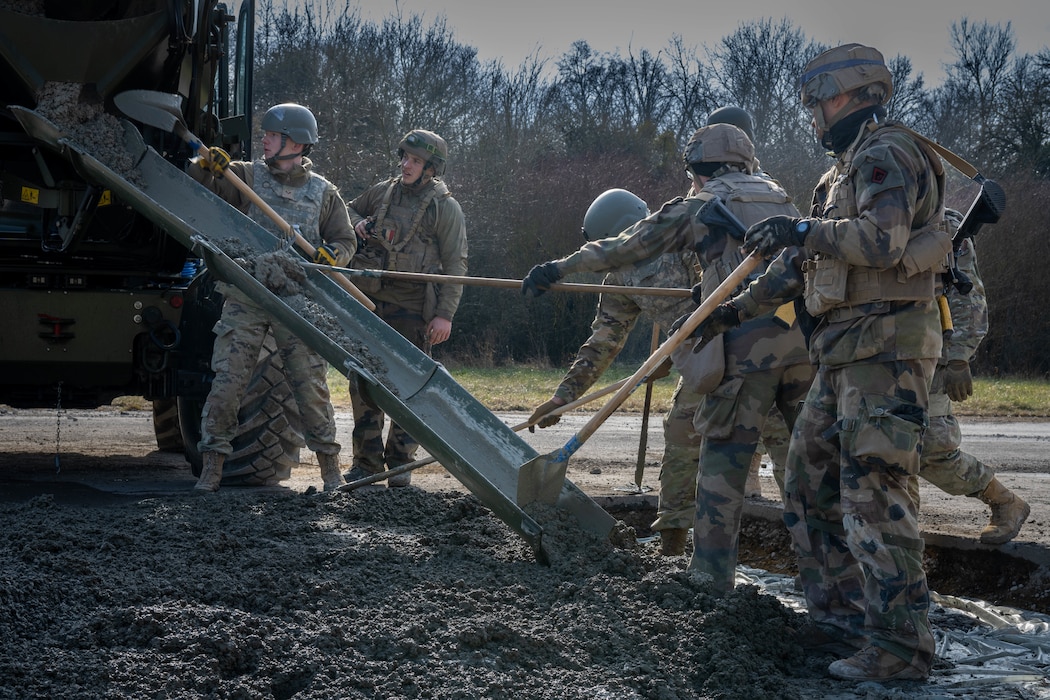 U.S. Air Force and French Army members spread concrete