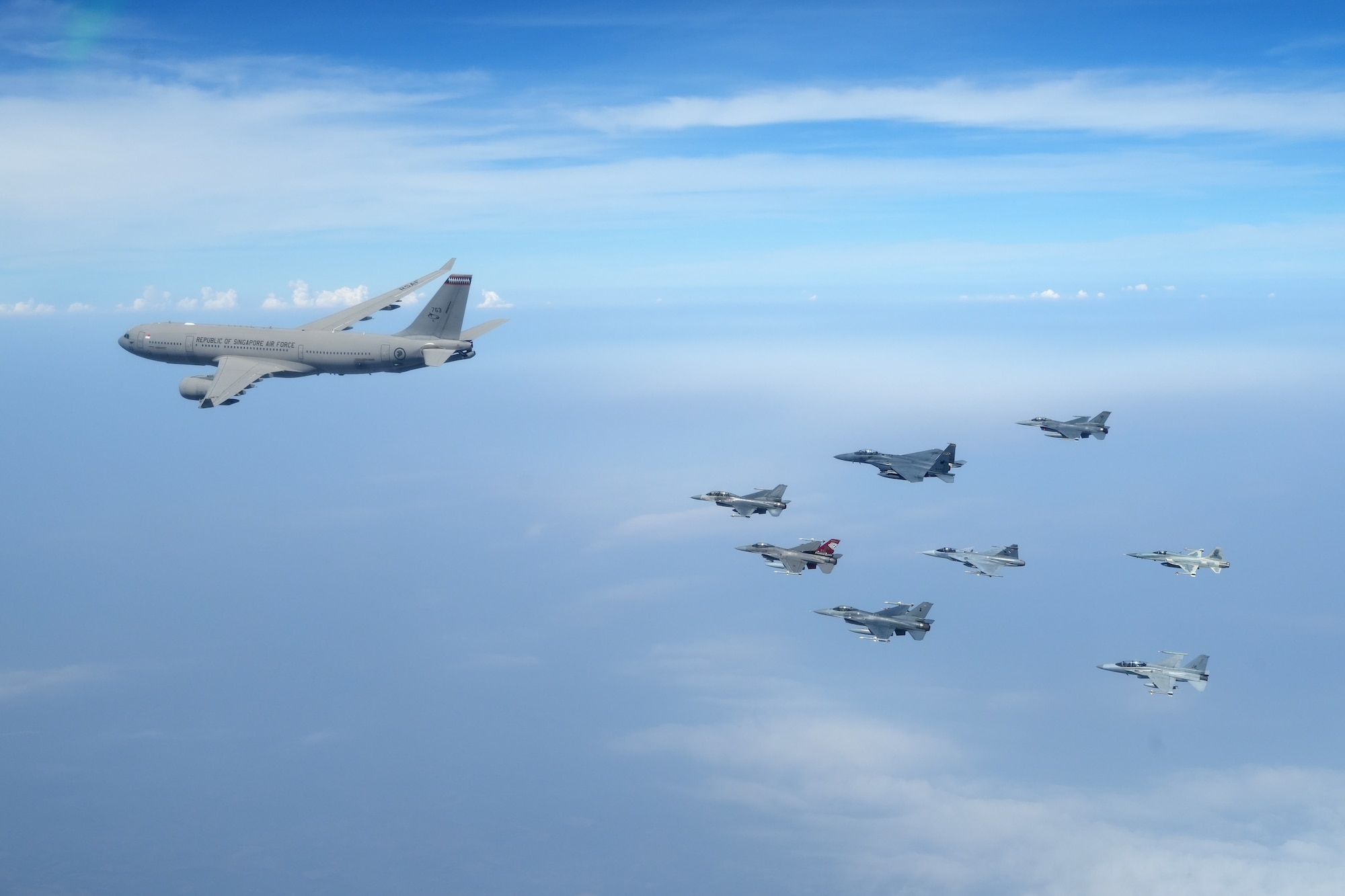 eight fighter jets fly in a wedge formation behind a large passenger plane