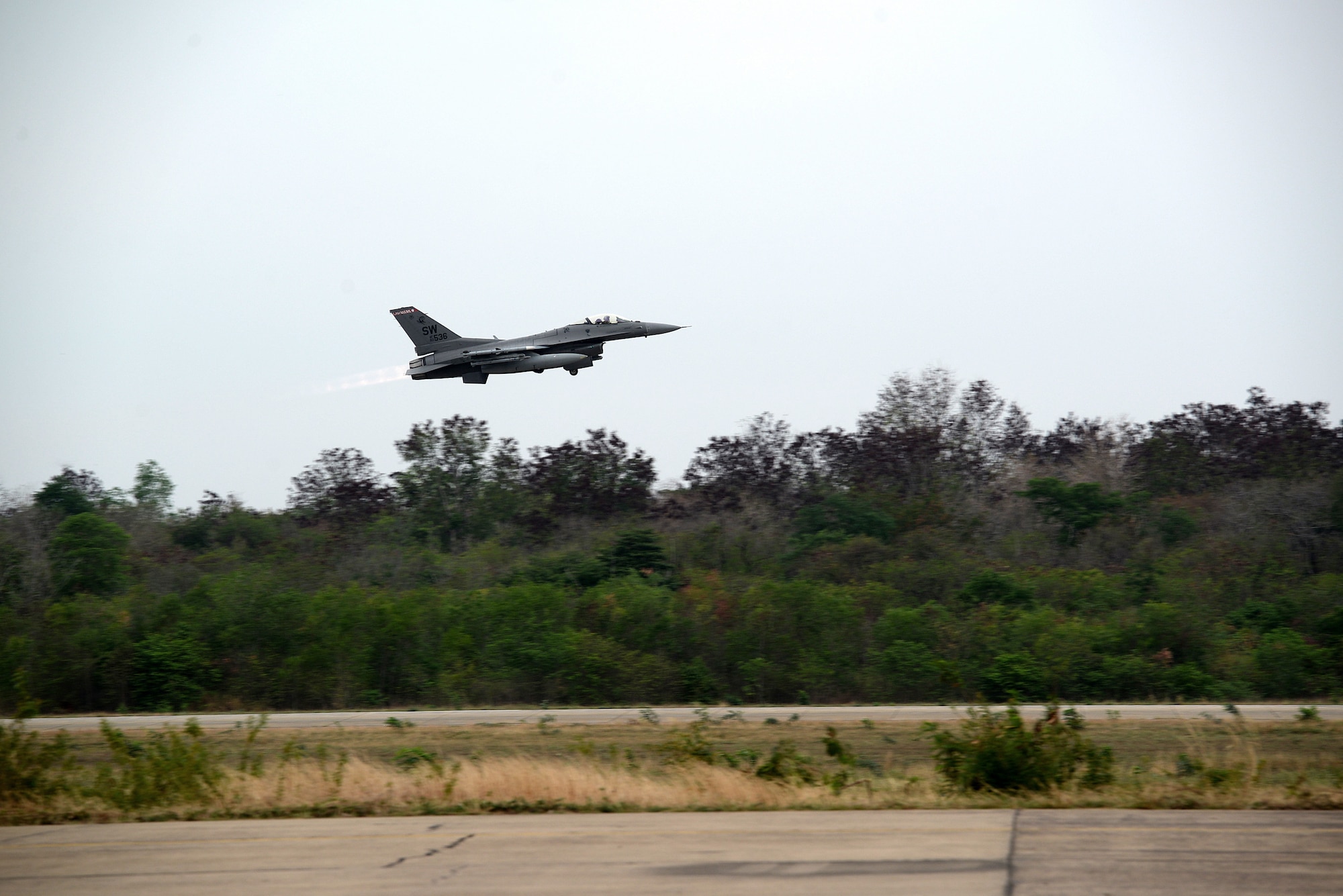 a fighter jet takes off from a runway in the middle of a jungle