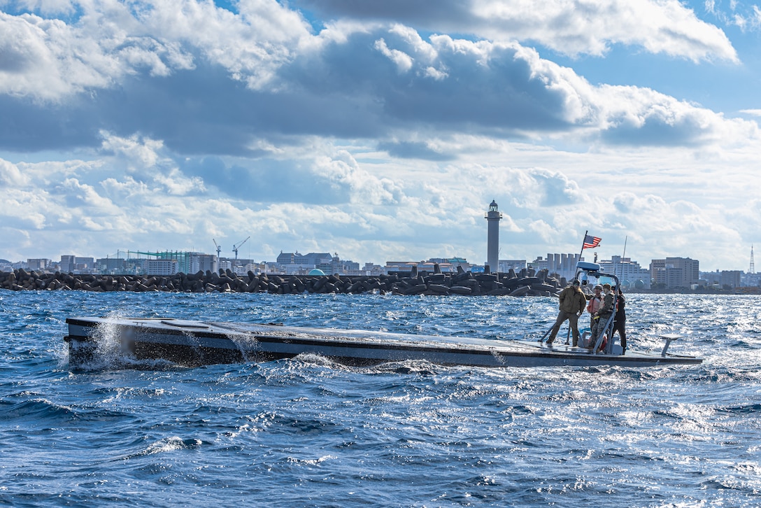 U.S. Marines operate an Autonomous Low-Profile Vessel at Naha Military Port, Okinawa, Japan, Jan. 17, 2025. Marines with 12th Littoral Logistics Battalion executed the first ALPV rehearsals in Okinawa, increasing 12th LLB's operational readiness and amphibious capabilities. The ALPV is a semi-submersible autonomous logistics delivery system that has the ability to deliver multiple variations of supplies and equipment through contested maritime terrain. The Marines are with 12th LLB, 12th Marine Littoral Regiment, 3d Marine Division. (U.S. Marine Corps photo by Lance Cpl. Rodney Frye) (Details on the vessel have been blurred for security reasons)