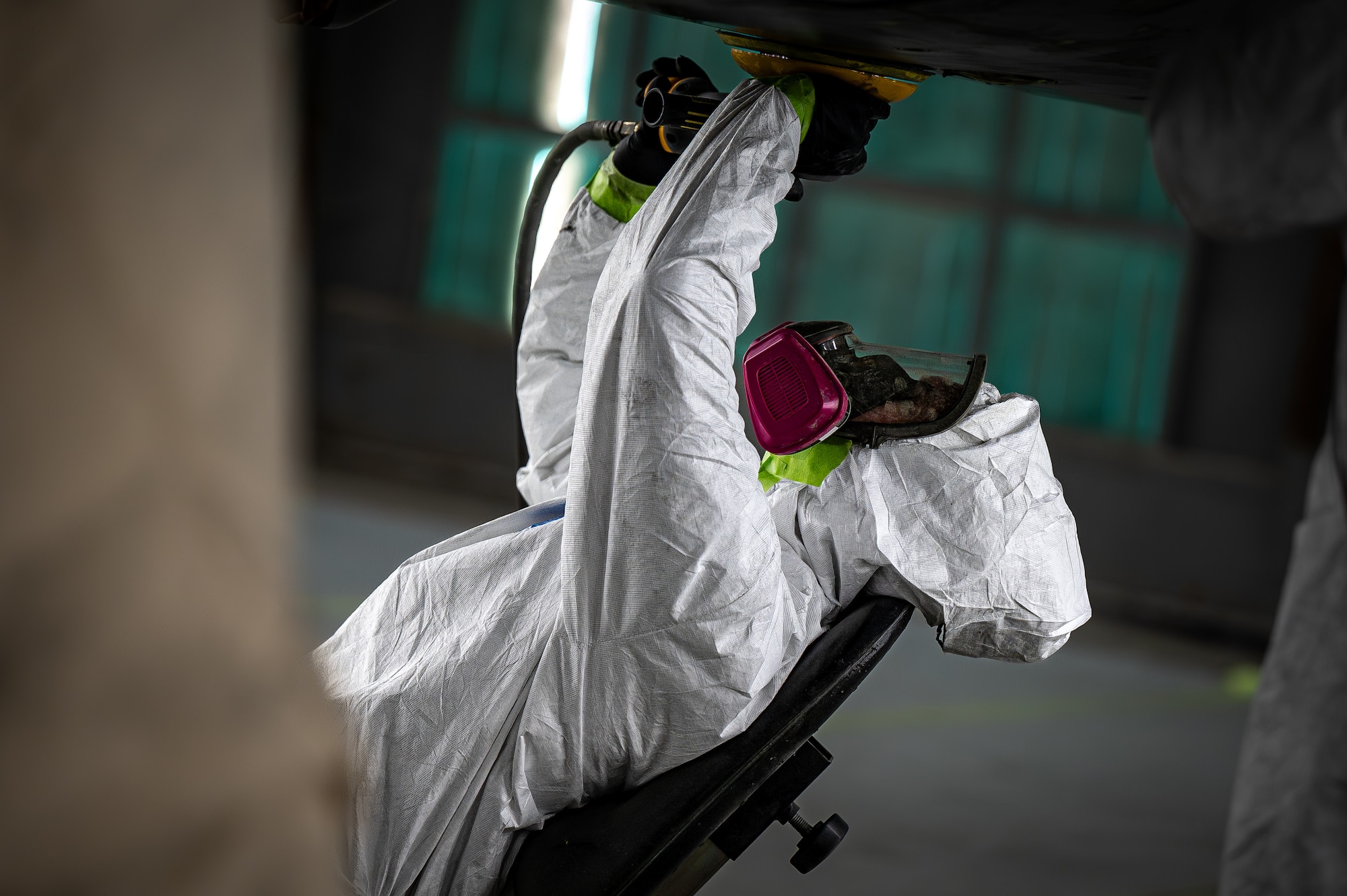 person wearing painting gear paints a jet.