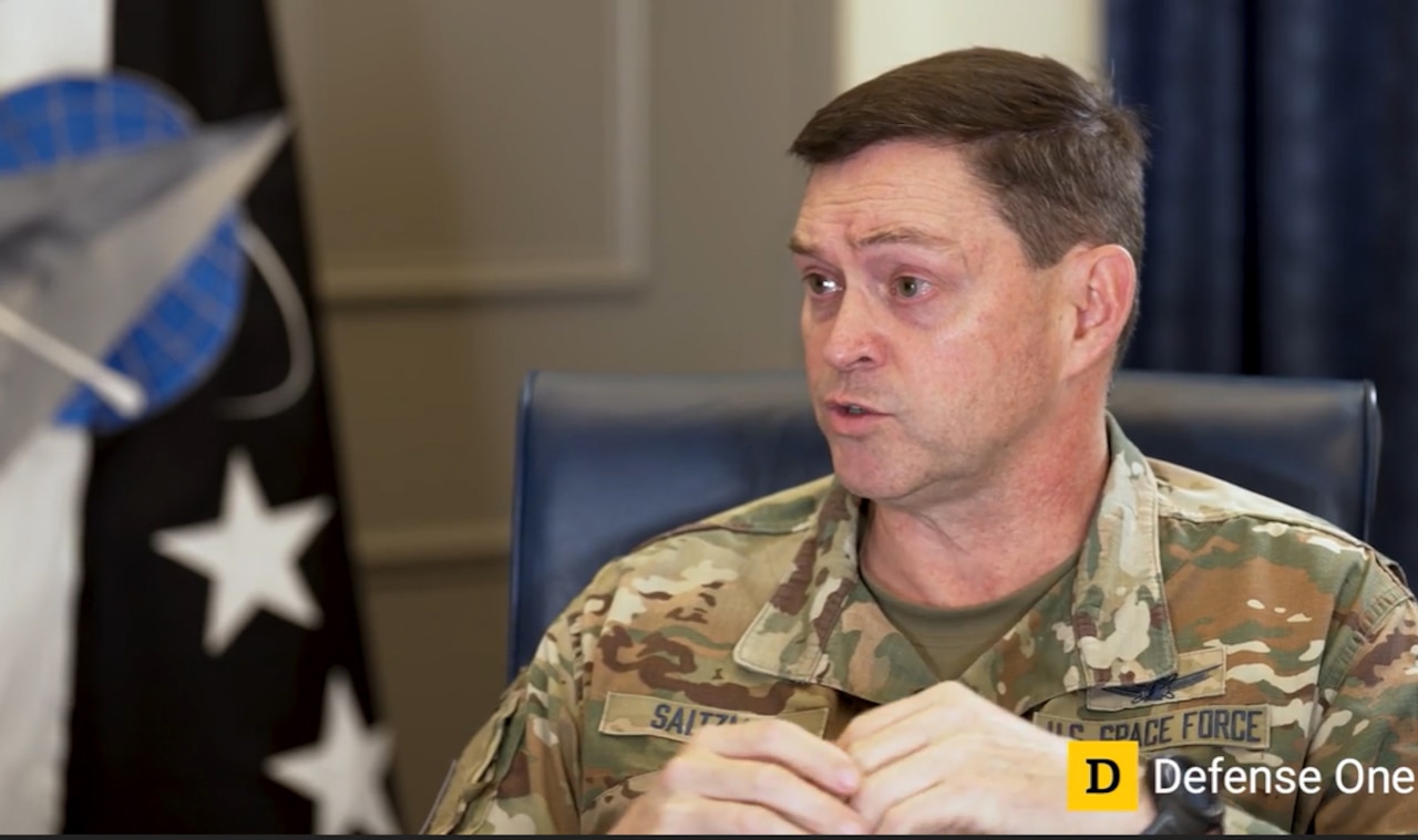 A man wearing a camouflage uniform speaks during a virtual event.