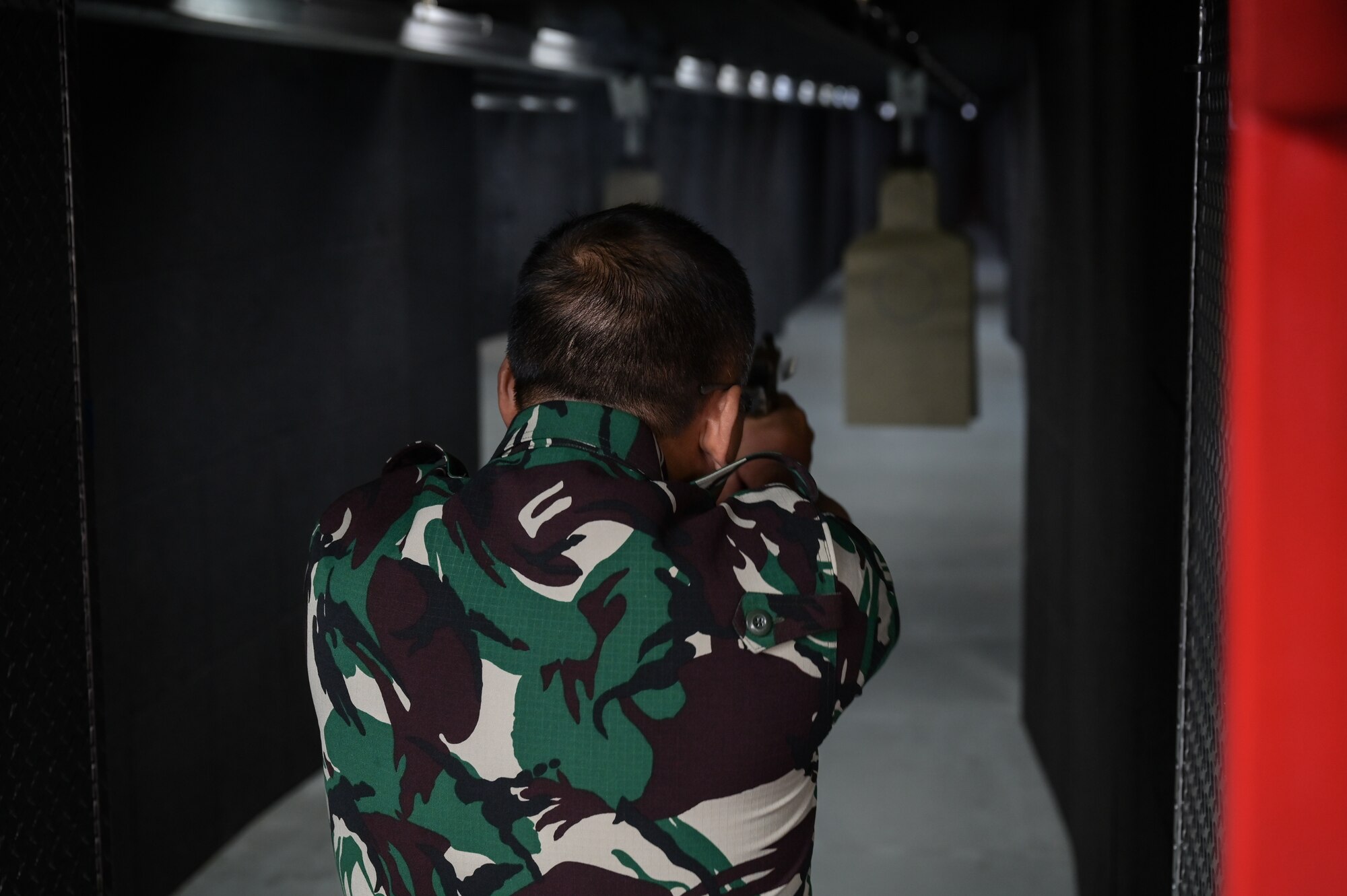 Indonesian Air Force representative fires a service pitol in an indoor range.