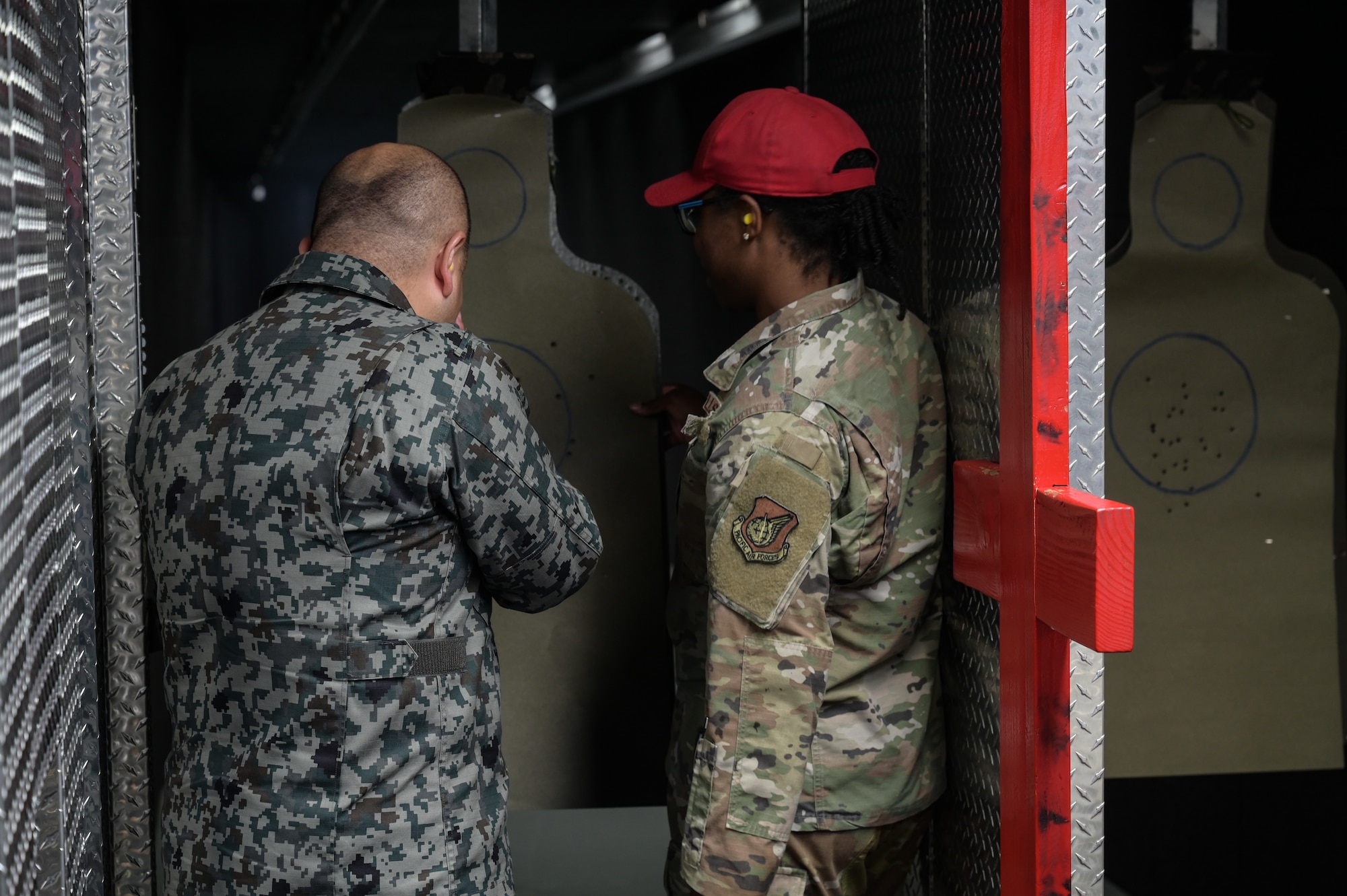 Airman reviews a target with bullet holes with a Japan Air Self-Defense Force representative in an indoor firing range.