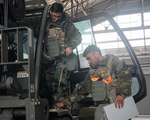 Airmen measure dimensions of a forklift.