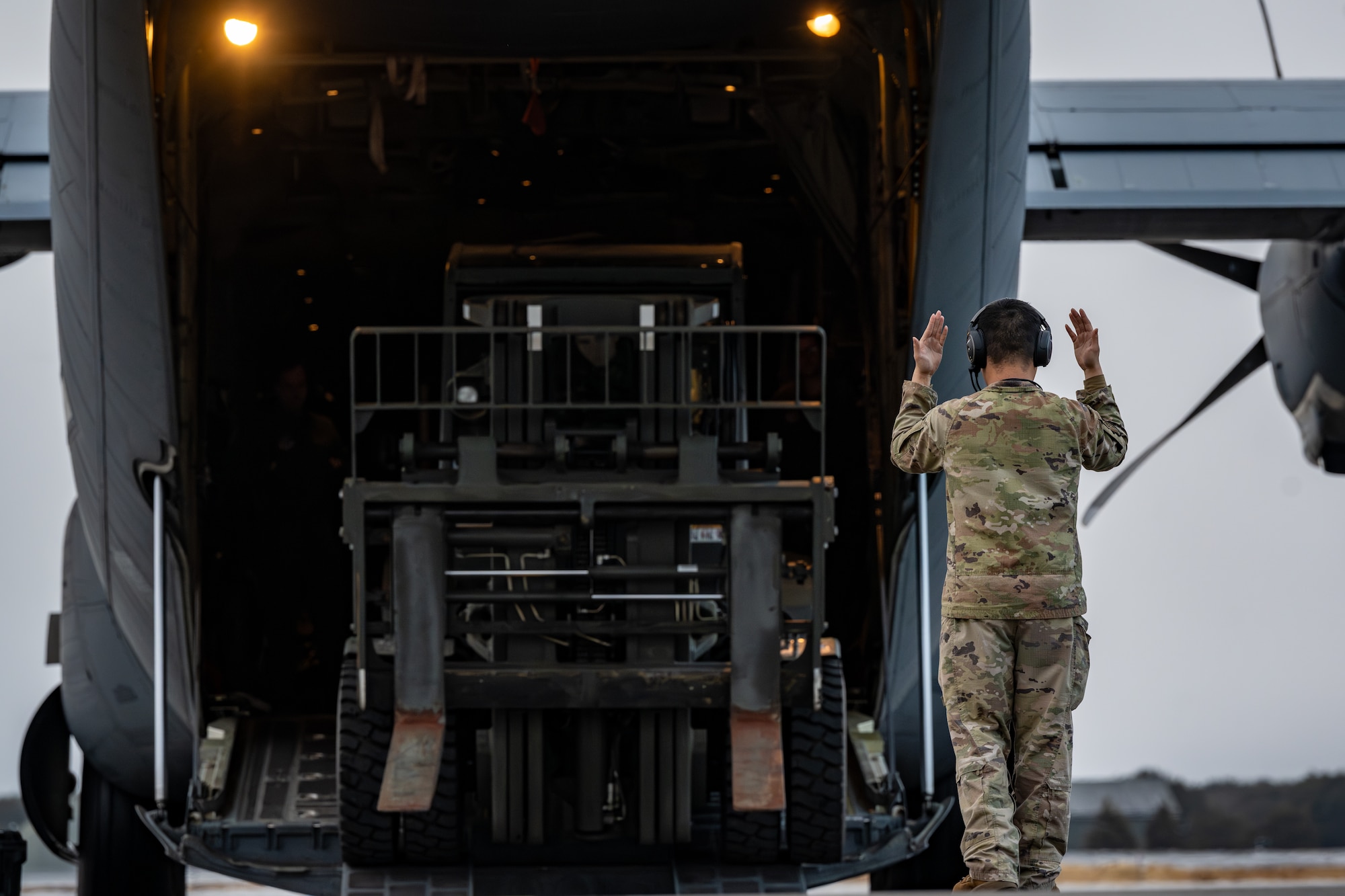 An Airman marshals a forklift out of a C-130J Super Hercules.