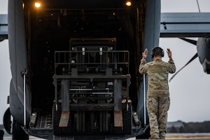 An Airman marshals a forklift out of a C-130J Super Hercules.