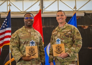 U.S. Air Force Senior Master Sgt. (select) Jonathan Tolliver, 380th Air Expeditionary Wing occupational safety manager, and Senior Master Sgt. (select) Jared Clark, 380th AEW weapons manager, pose with their promotion plaques during a Senior Master Sgt. release ceremony in the U.S. Central Command area of responsibility, Feb. 28, 2025. The ceremony recognized individuals for their hard work and commitment as they prepared to step into senior leadership roles. (U.S. Air Force photo by Senior Airman Sir Wyrick)