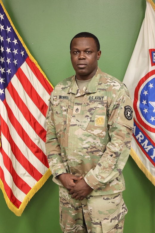 Male U.S. Army Soldier in uniform poses with American Flag and USAREC Flag behind him