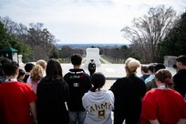 A large crowd (foreground) is watching a U.S. Army Soldier in dark blue ceremonial dress uniform at the Tomb of the Unknown Soldier.