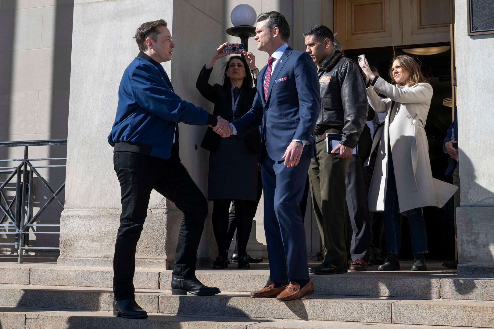 Defense Secretary Pete Hegseth shakes Elon Musk's hand on the steps outside the Pentagon.