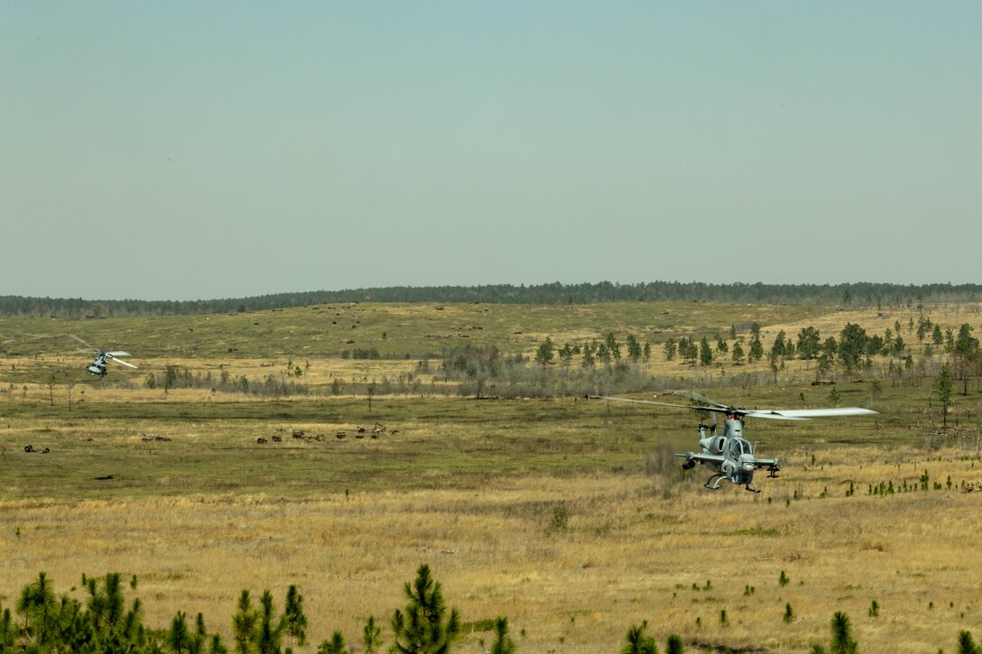 A U.S. Marine Corps AH-1Z Viper attack helicopter, right, and a UH-1Y Venom utility helicopter with Marine Light Attack Helicopter Squadron (HMLA) 773, 4th Marine Aircraft Wing, Marine Forces Reserve, maneuver to conduct live-fire shooting drills during a field exercise on Camp Shelby Joint Forces Training Center, Mississippi, March 11, 2025. MARFORRES Marines conducted the exercise to maintain proficiency in warfighting, communication and leadership skills common to all Marines. (U.S. Marine Corps photo by Lance Cpl. Van Hoang)