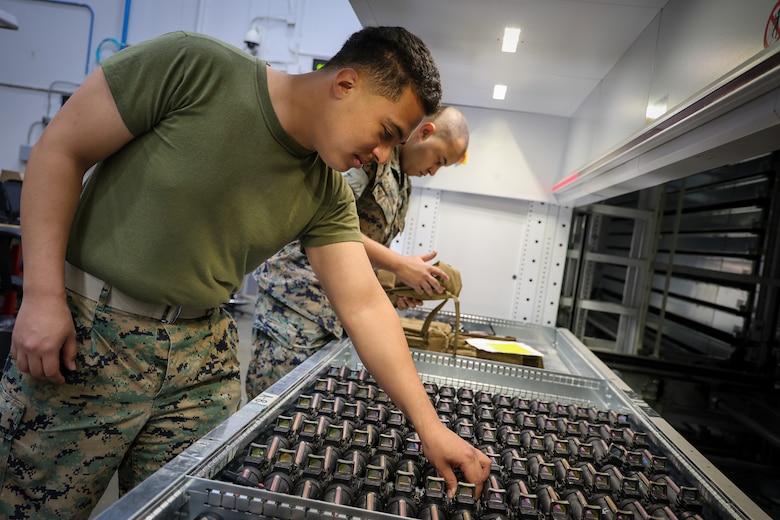 Lance Cpl. Charlie Hidalgo, a supply chain management specialist, and Lance Cpl. Jeremiah B. Robinson, an inventory management specialist, places assets in their proper locations. The vertical lift modules (VLMs) assist in sorting and organizing assets using condition codes and National Item Identification Numbers (NIINs). The VLMs optimize warehouse space while storing more than 70,000 assets valued at over $200 million.